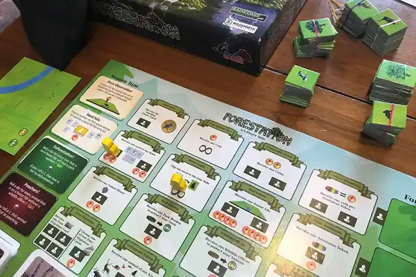 The Forestation game board with action spaces like Buy Seeds, Real Estate, Park Warden and Wildlife Officer, yellow worker pieces, and stacks of tree and animal tiles
